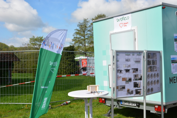 Im Bild ist der Anhänger der SVD zu sehen. Er ist mintgrün. Davor sind links und rechts Plakate und eine Beachflag zu sehen. 