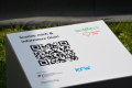 Das Bild zeigt einen großen QR-Code auf weißem Hintergrund mit der Aufforderng