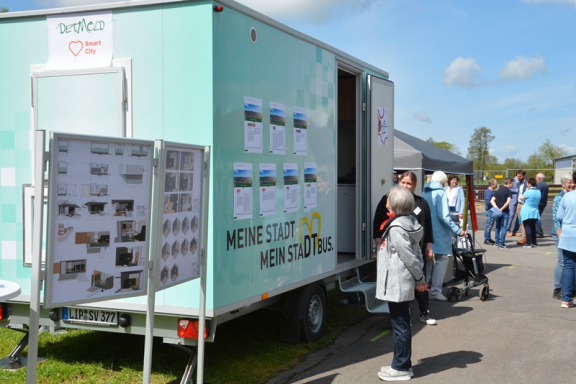 Man sieht die abgesperrte Straße des Ortsteilfestes in Brokhausen, auf der mehrere Menschen flanieren. Links im Bild ist der Anhänger der SVD zu sehen. Er ist mintgrün. 