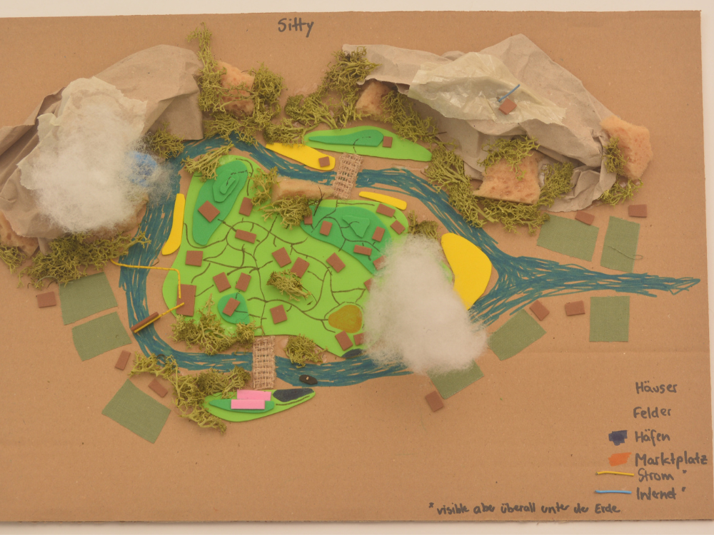 Das Foto zeigt das gebastelte Stadtmodell "Sitty" eines Teilnehmers, das mit vielen Materialien wie Watte, Kartonschnipseln, Moos und bunten Pappen erstellt wurde.