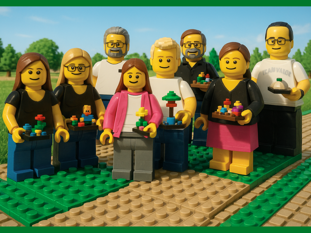 Acht Teammitglieder stehen im Freien auf gepflastertem Weg, halten ihre bunten LEGO-Modelle und lächeln. Das Foto wurde mit KI in die LEGO-Welt übertragen.