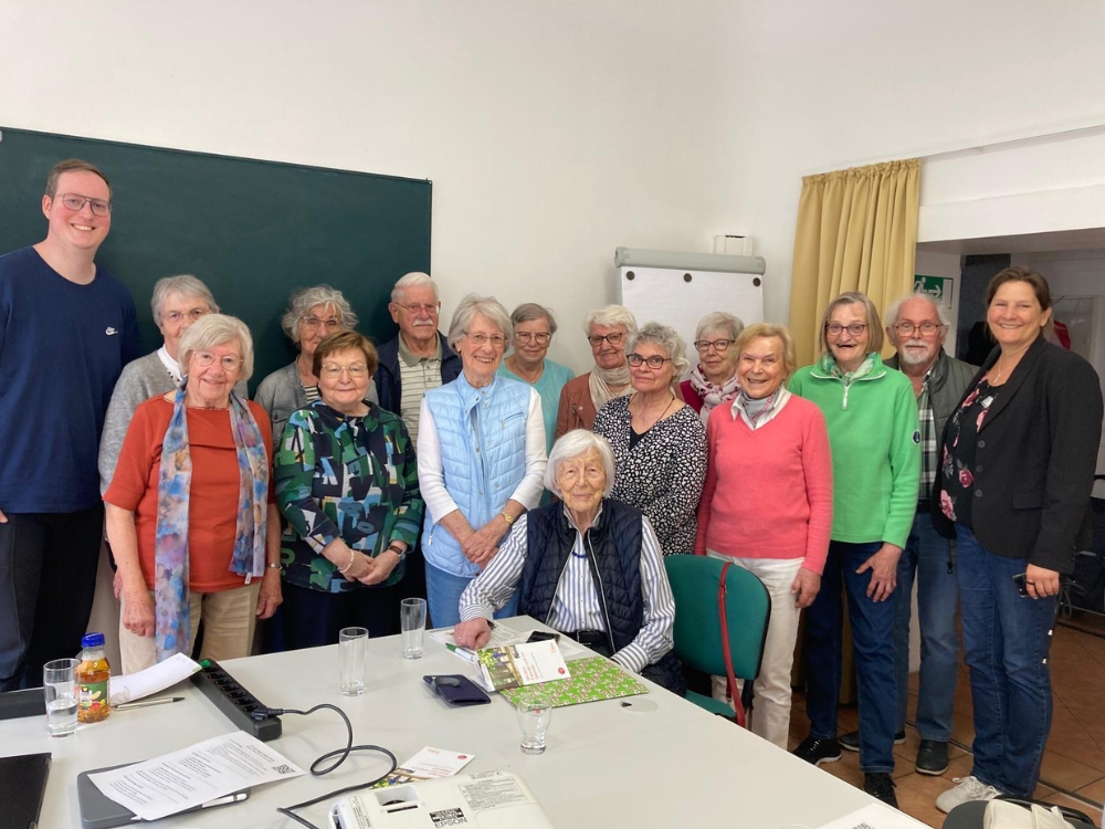 Das Gruppenfor vor einer weißen Wand zeigt die 14 Teilnehmenden der Digitalen Erlebnisreihe zum Thema "QR-Codes". Die beiden Referenten Pierre Rotthoff (links) und Tanja Watermann (rechts) rahmen die Gruppe ein. 