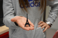 Ein junges Mädchen balanciert einen vom 3D-Drucker ausgedruckten Eifelturm auf ihrer Hand und streckt diesen Richtung Kamera. Sie trägt einen grauen Pullover. Ihr Gesicht  ist nicht zu sehen. 